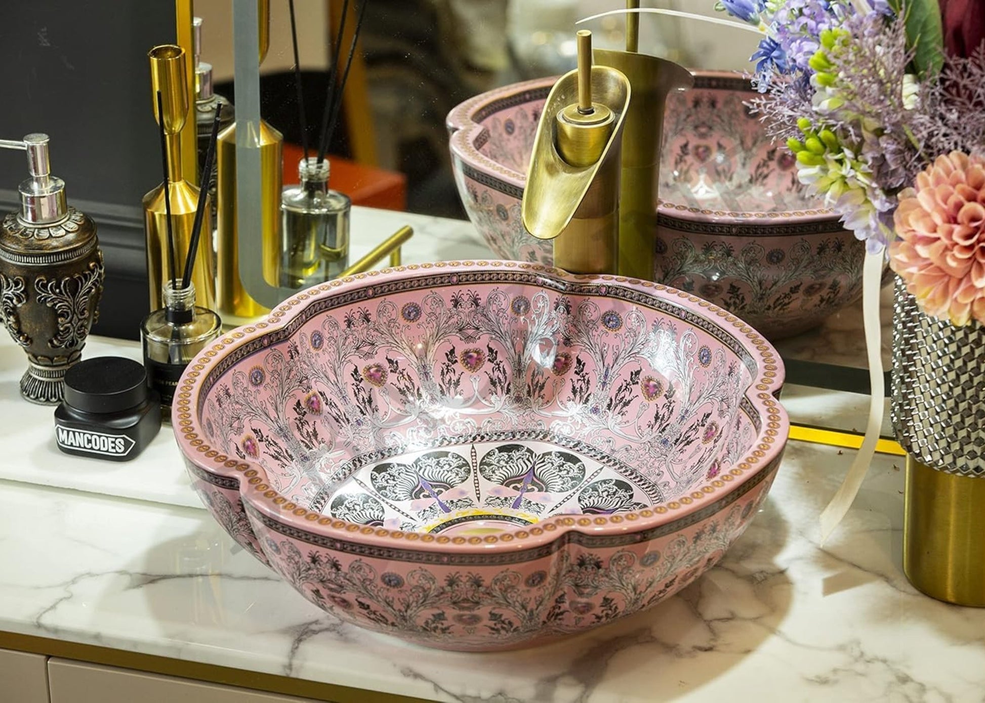 Decorative pink sink with intricate patterns on a marble countertop.
